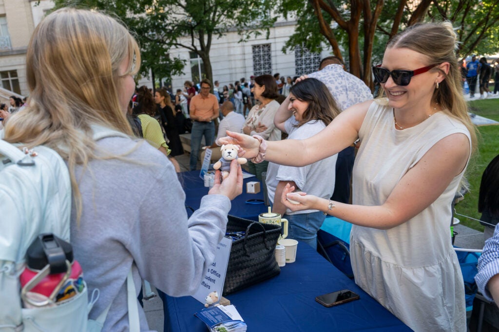 A student receiving a promotional keychain from a student affairs team member